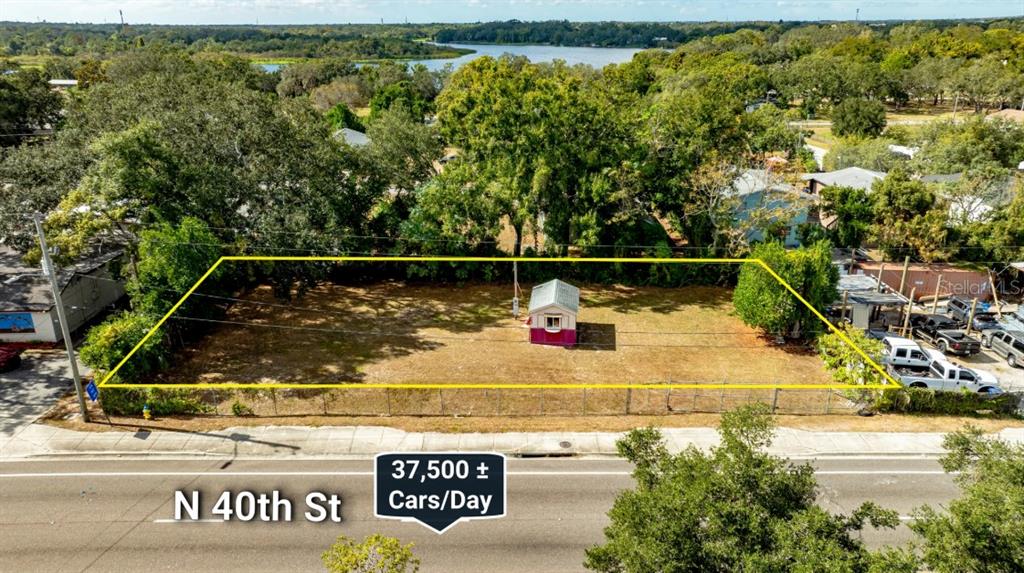 An aerial view shows a fenced, vacant rectangular lot with a small shed on N 40th St — 8428 N 40TH STREET, TAMPA, FL