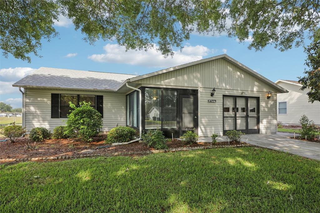 A single-story house with light siding, a screened-in porch, and a paved driveway — 1907 TWEED COURT, LEESBURG, FL