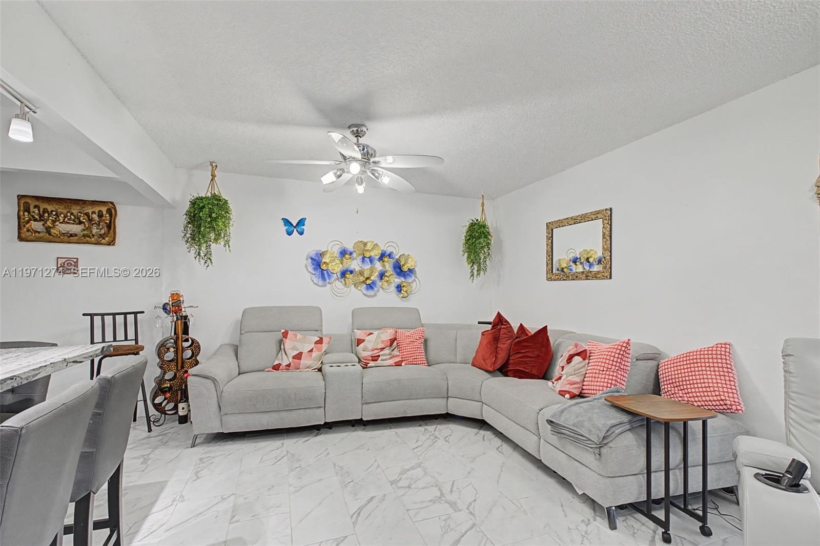 A living room features a gray sectional sofa, marble-look tile flooring, and decorative wall art — 399 NW 72nd Ave # 320, Miami FL 33126, MIAMI, FL