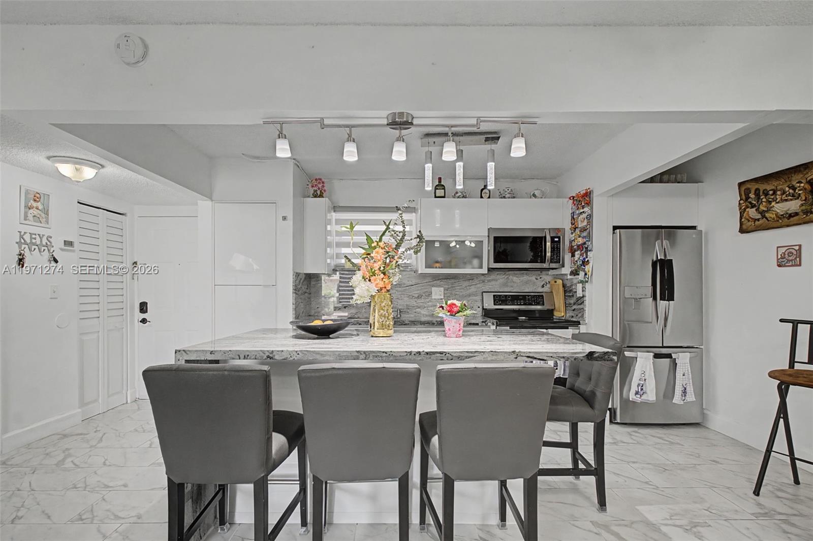 A kitchen features a marble-topped island with four gray chairs and stainless steel appliances — 399 NW 72nd Ave # 320, Miami FL 33126, MIAMI, FL