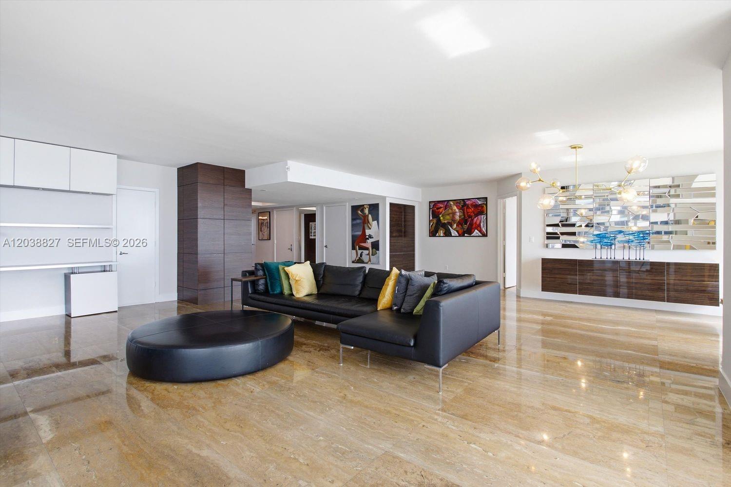 A modern living room features a black sectional sofa, a large ottoman, and polished floors — 50 Biscayne Blvd # 2510, Miami FL 33132, MIAMI, FL