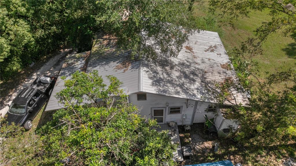 An aerial view shows a single-story house with a metal roof surrounded by trees — 6226 SW 34TH STREET, GAINESVILLE, FL