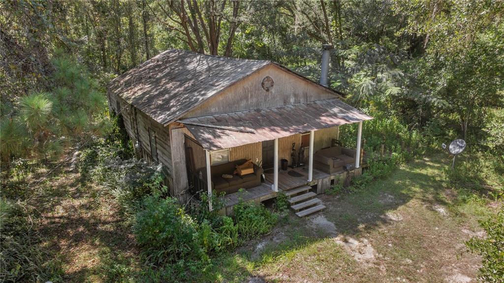An aerial view of a weathered, rustic wooden cabin with a front porch and metal roof — 6226 SW 34TH STREET, GAINESVILLE, FL
