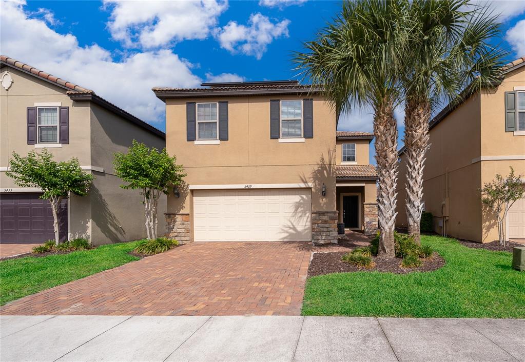 A two-story tan stucco house with a two-car garage and palm trees in the front — 5429 MISTY OAK CIRCLE, DAVENPORT, FL