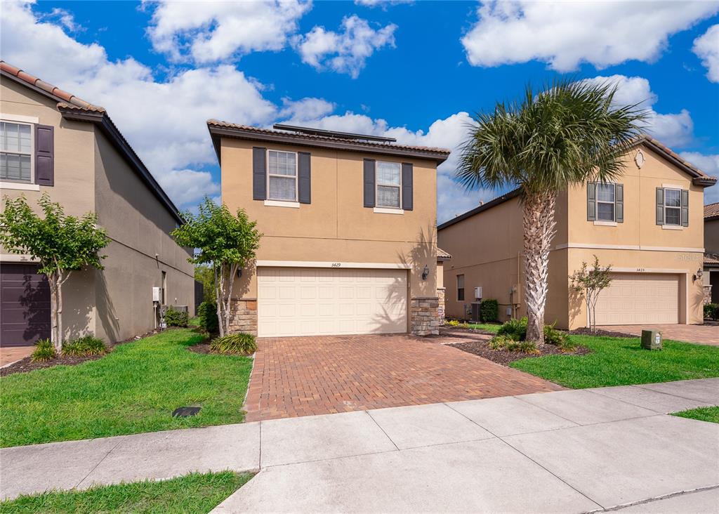 A two-story tan stucco house with a brick paver driveway and a two-car garage — 5429 MISTY OAK CIRCLE, DAVENPORT, FL