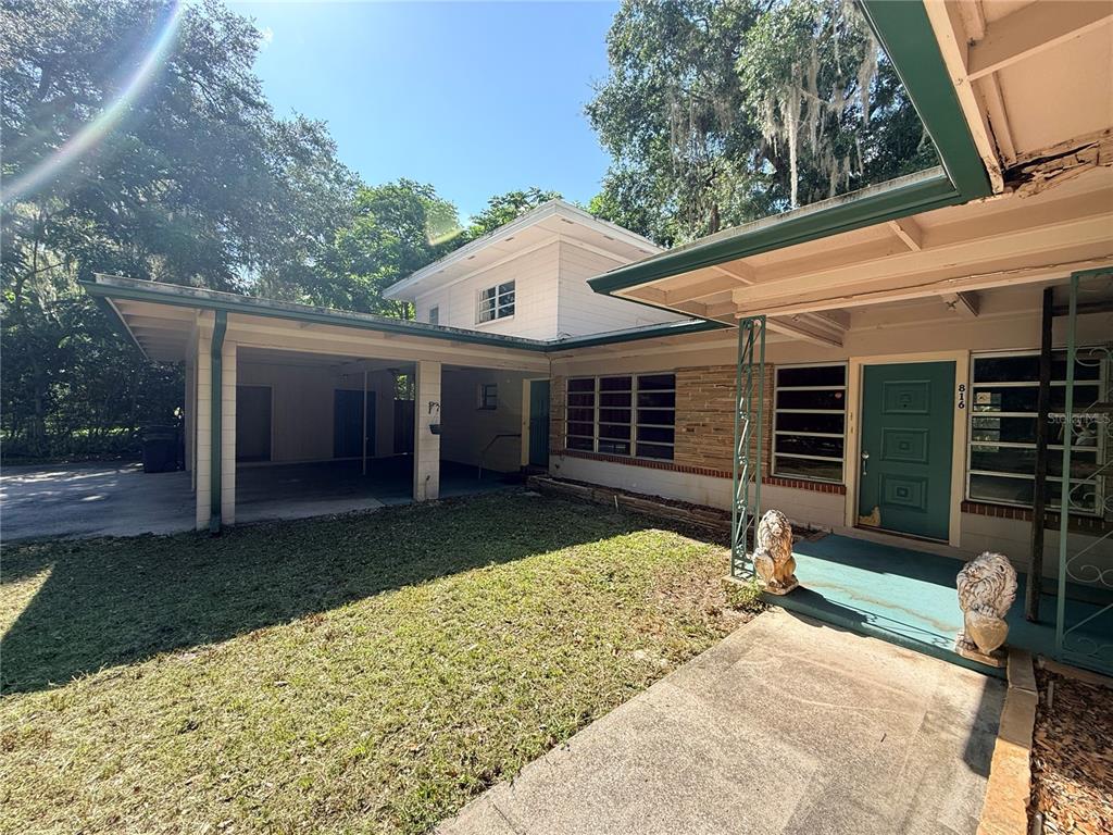 A single-story house with a carport, stone facade, and a teal front door — 816 NW 14TH AVE., GAINESVILLE, FL