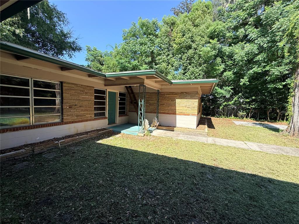A single-story house with stone siding, a green door, and a covered entryway — 816 NW 14TH AVE., GAINESVILLE, FL