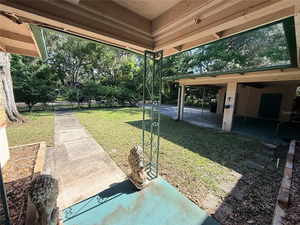 A covered porch with decorative metal supports and lion statues overlooks a lawn and driveway — 816 NW 14TH AVE., GAINESVILLE, FL