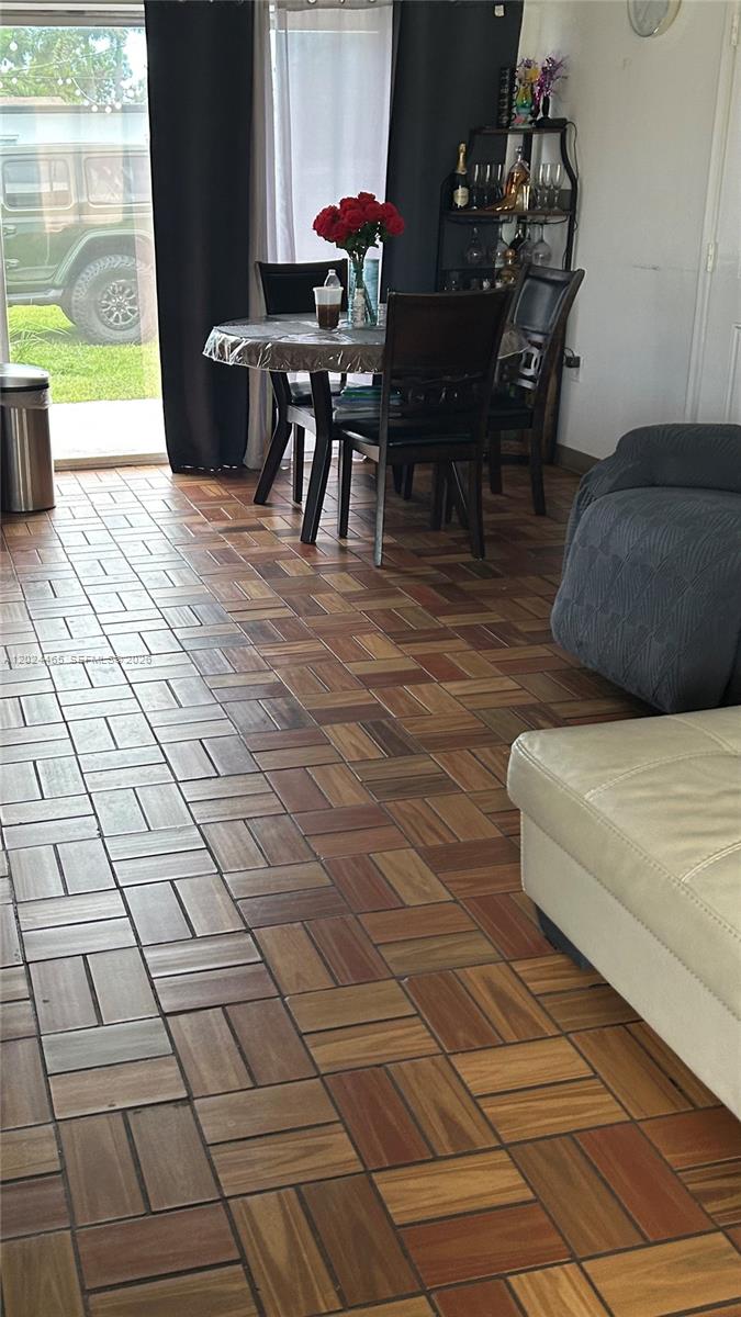 A dining area and living space feature wood-look parquet flooring and a sliding glass door — 11750 SW 186th St, Miami FL 33177, MIAMI, FL