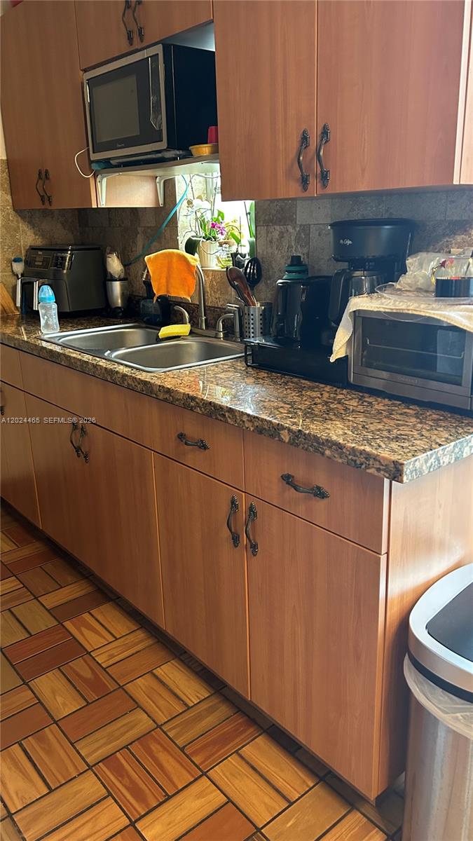 A kitchen features wood cabinets, granite countertops, a double sink, and tiled flooring — 11750 SW 186th St, Miami FL 33177, MIAMI, FL