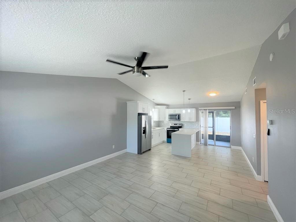 An open-concept kitchen and living area features light gray walls, tile flooring, and white cabinetry — 130 E 17TH STREET UNIT 132, ST CLOUD, FL