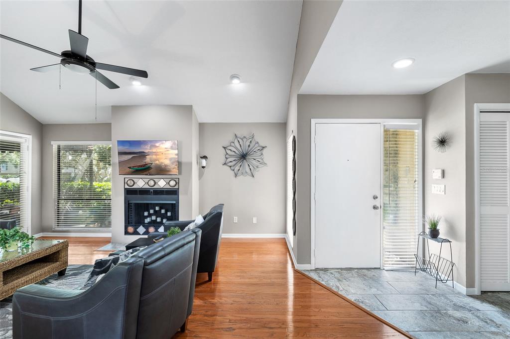 A living room features a vaulted ceiling, a fireplace with a mounted television, and furniture — 11520 GALLERIA DRIVE, TAMPA, FL