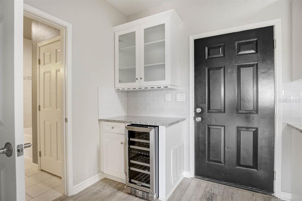 A small kitchen area features white cabinets, a wine cooler, and a black exterior door — 4311 BAYSIDE VILLAGE DRIVE UNIT 303, TAMPA, FL