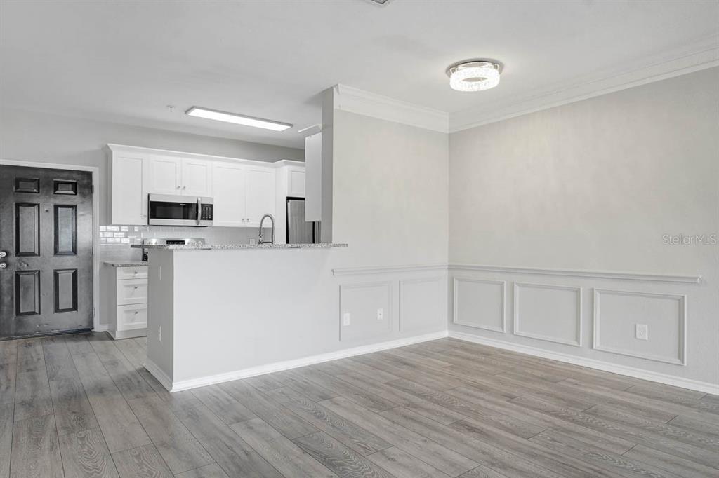 A kitchen features white cabinets, stainless steel appliances, granite countertops, and light wood-look flooring — 4311 BAYSIDE VILLAGE DRIVE UNIT 303, TAMPA, FL