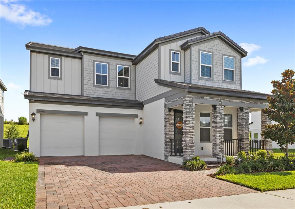 A two-story house features a brick paver driveway, a two-car garage, and stone-accented porch columns — 16043 SILVER BROOK WAY, WINTER GARDEN, FL
