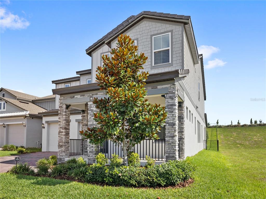 A two-story house with a stone-accented porch, a large magnolia tree, and a grassy yard — 16043 SILVER BROOK WAY, WINTER GARDEN, FL