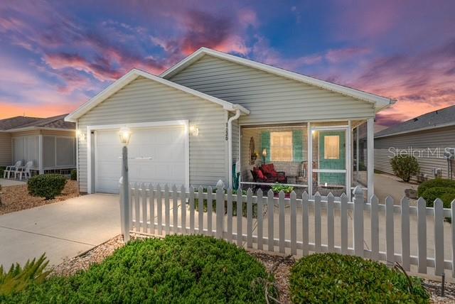 A single-story house with light siding and a white picket fence at sunset — 1636 ABASCO COURT, THE VILLAGES, FL