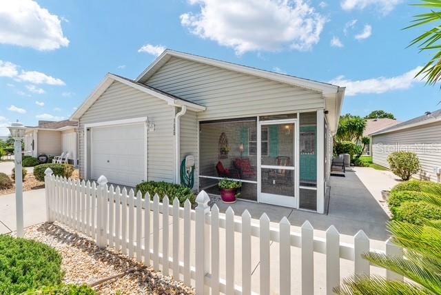 A light-colored house with a white picket fence and a screened-in front porch — 1636 ABASCO COURT, THE VILLAGES, FL