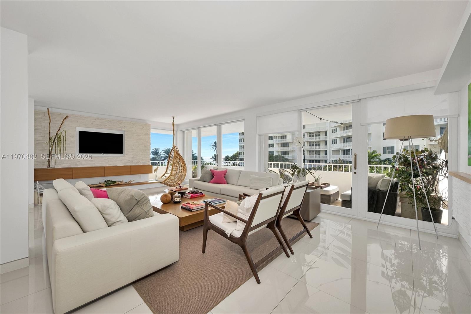 A bright living room features white tile floors, a stone accent wall, and a balcony — 199 Ocean Lane Dr # 401, Key Biscayne FL 33149, KEY BISCAYNE, FL