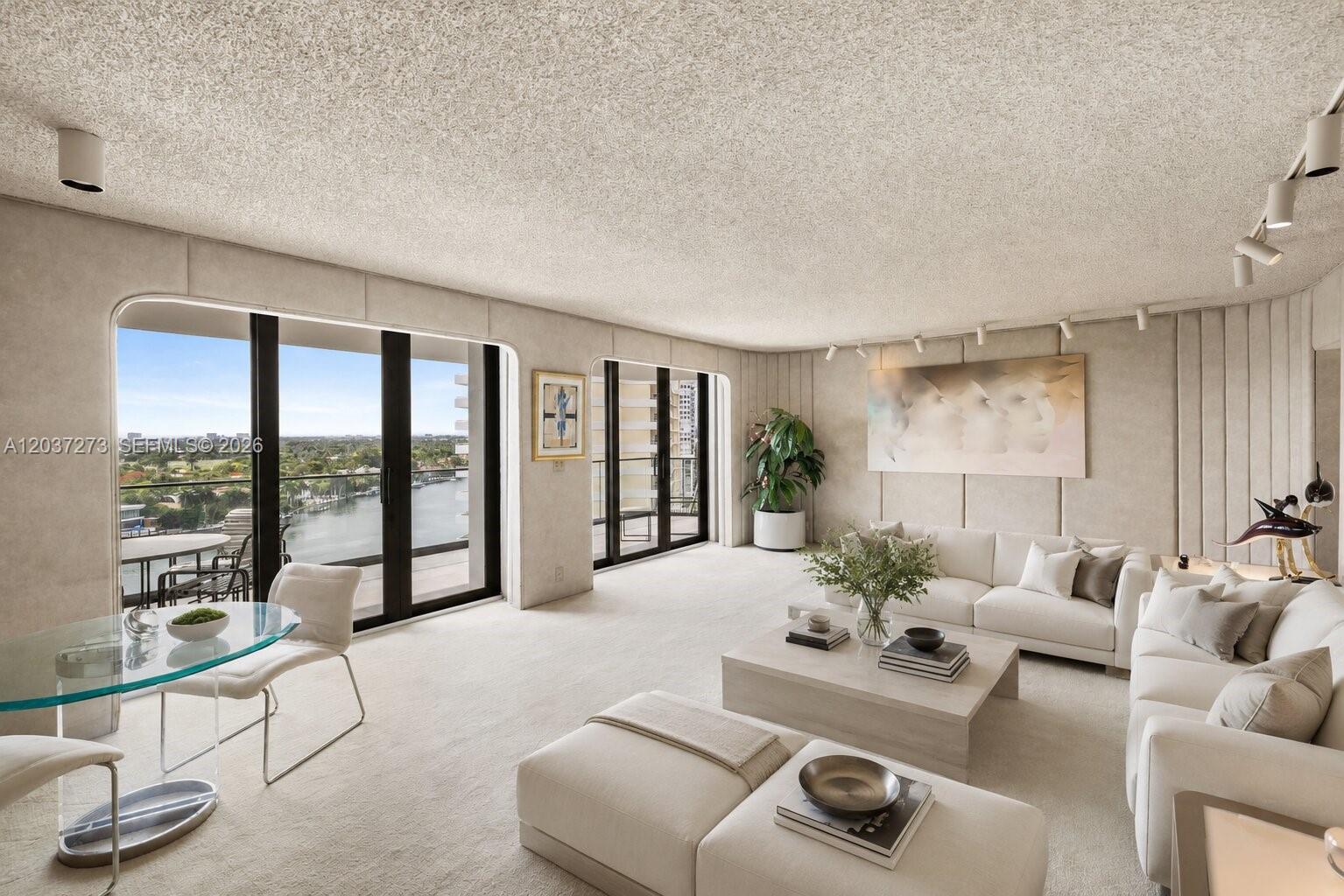 A bright living room features neutral carpeting, white sofas, and large sliding glass balcony doors — 5500 Collins Ave # 1401, Miami Beach FL 33140, MIAMI BEACH, FL