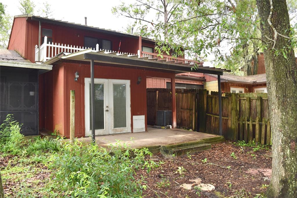 A red two-story house features a covered patio with French doors and a wooden fence — 4614 SW 67TH TERRACE, GAINESVILLE, FL