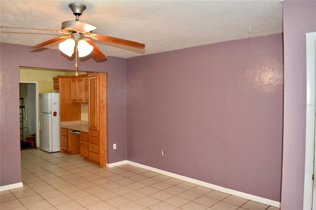A room with purple walls, a ceiling fan, and tile flooring, opening into a kitchen area — 4614 SW 67TH TERRACE, GAINESVILLE, FL