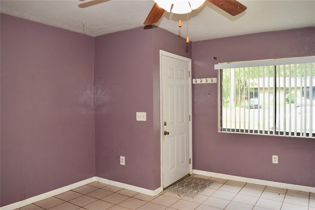 A room with purple walls, tile flooring, a ceiling fan, and a white entry door — 4614 SW 67TH TERRACE, GAINESVILLE, FL