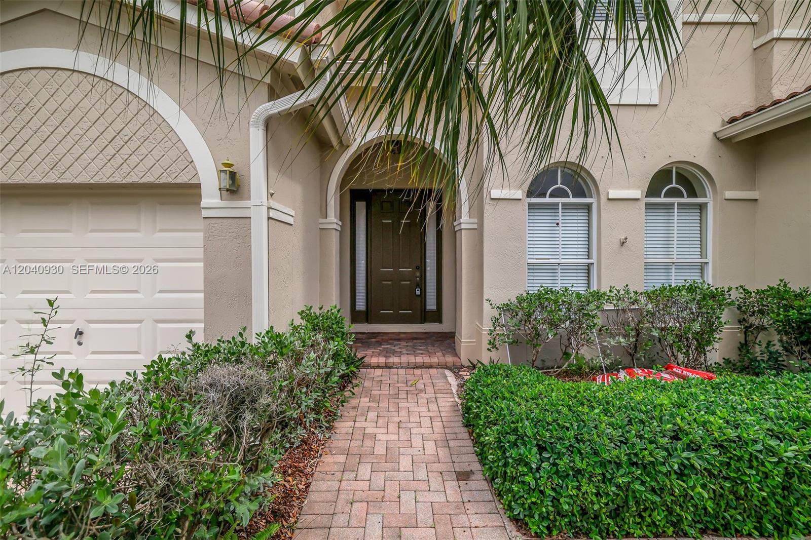 A brick walkway leads to the arched front entrance of a beige stucco house — 12361 SW 123rd Ter, Miami FL 33186, MIAMI, FL