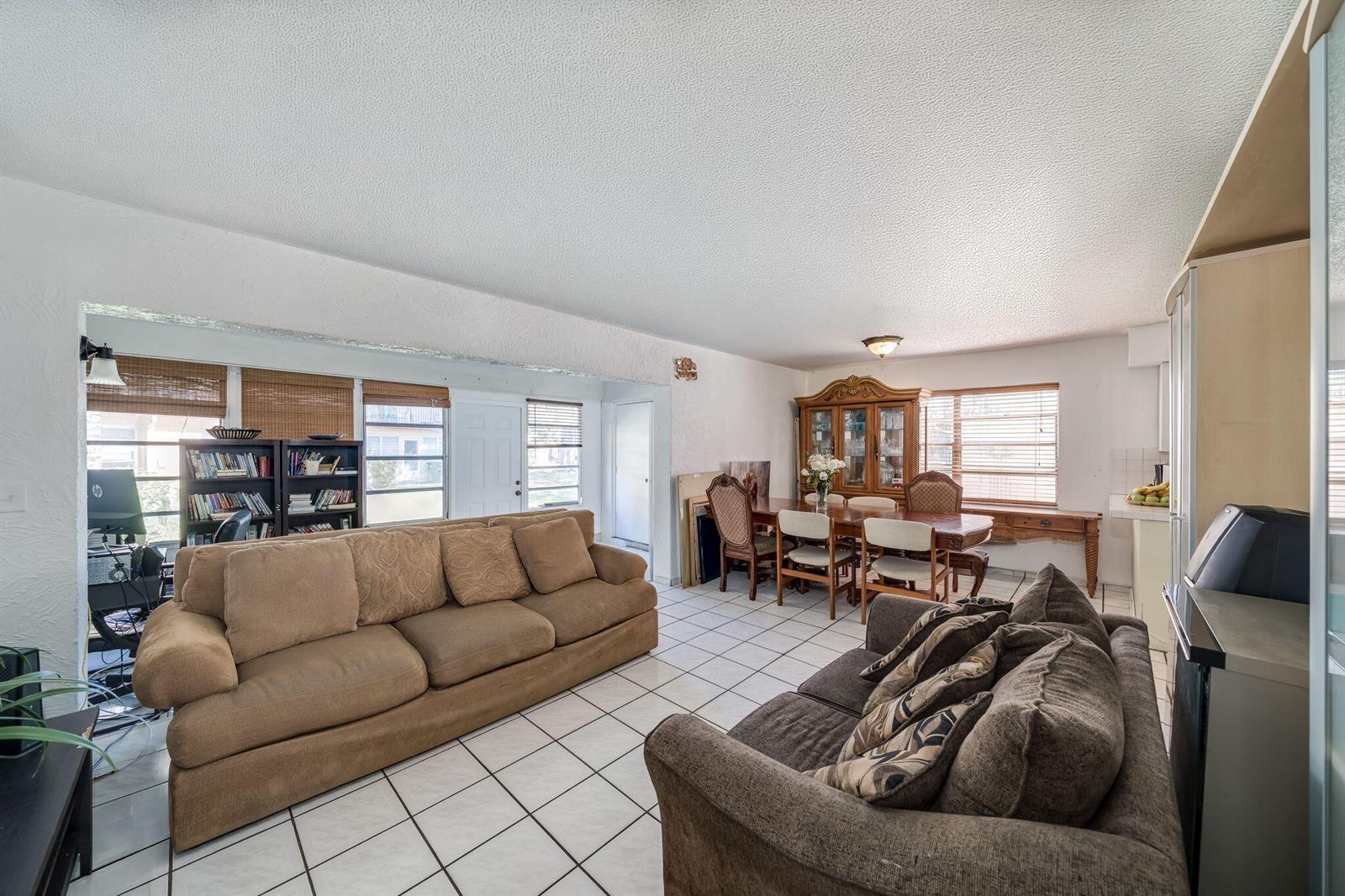 A living and dining room with white tile floors, textured ceilings, and two brown sofas — 7 Ann Lee Lane, Tamarac FL 33319, TAMARAC, FL