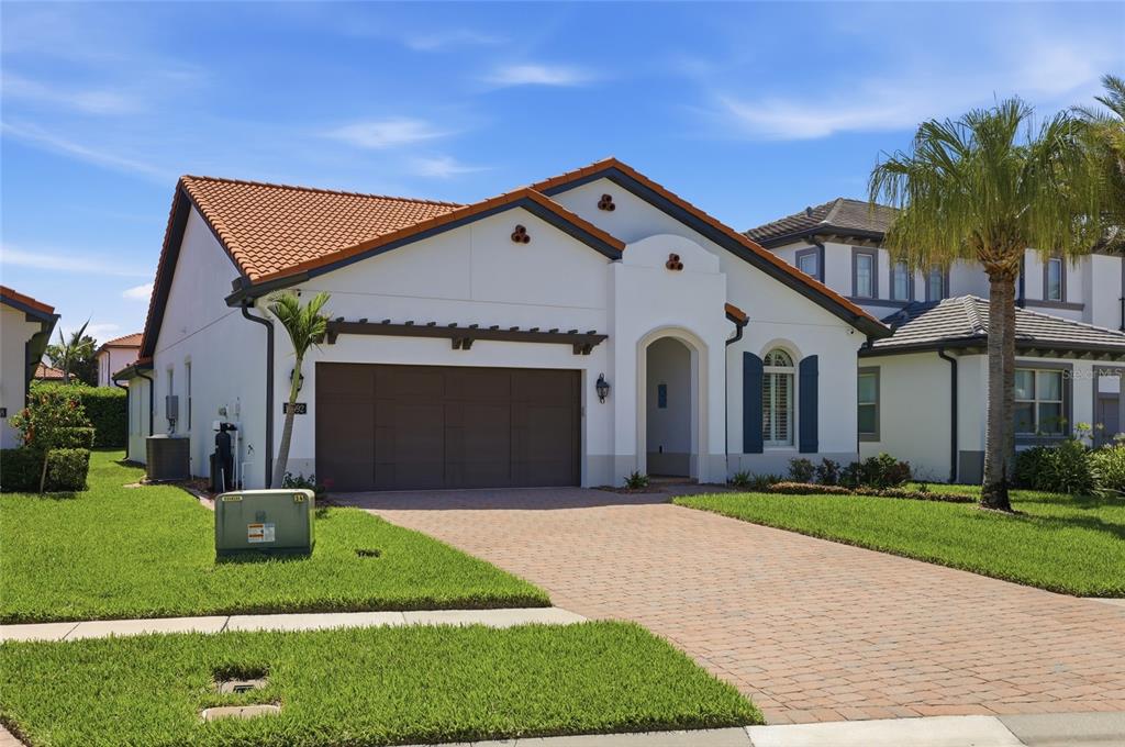A single-story house with a terracotta tile roof, a brown garage door, and a paved driveway — 10692 ROYAL CYPRESS WAY, ORLANDO, FL