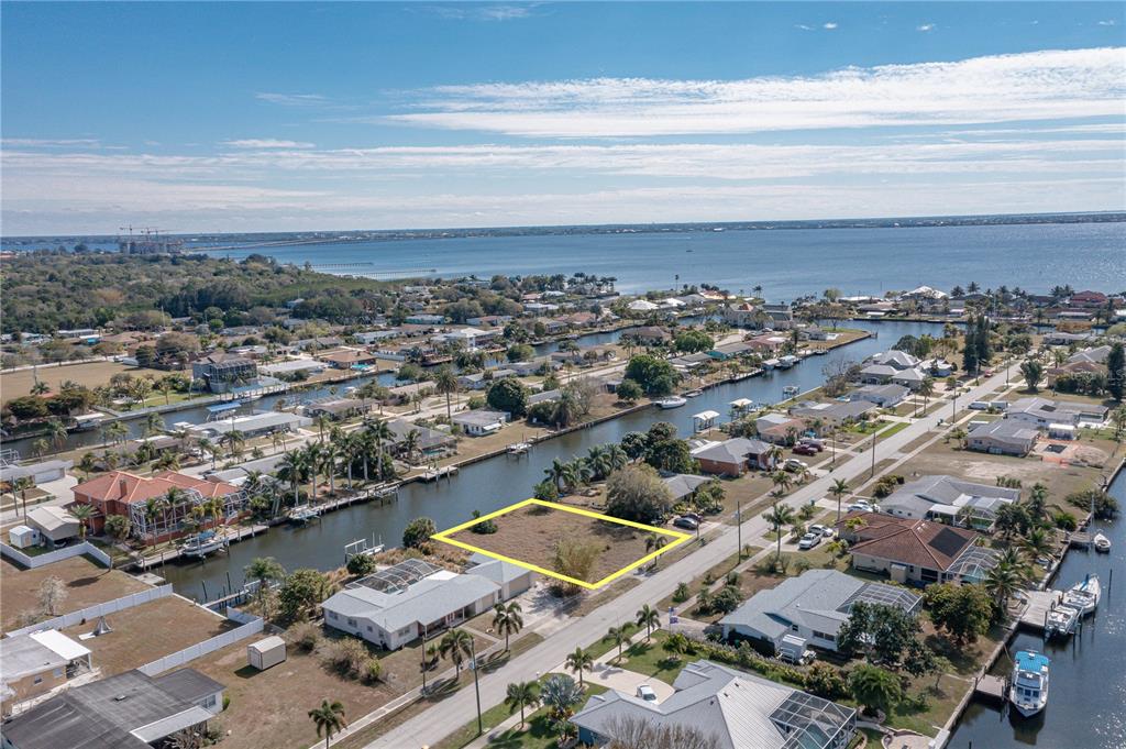 An aerial view shows a vacant residential lot outlined in yellow near a canal — 109 BALDWIN COURT SE, PORT CHARLOTTE, FL