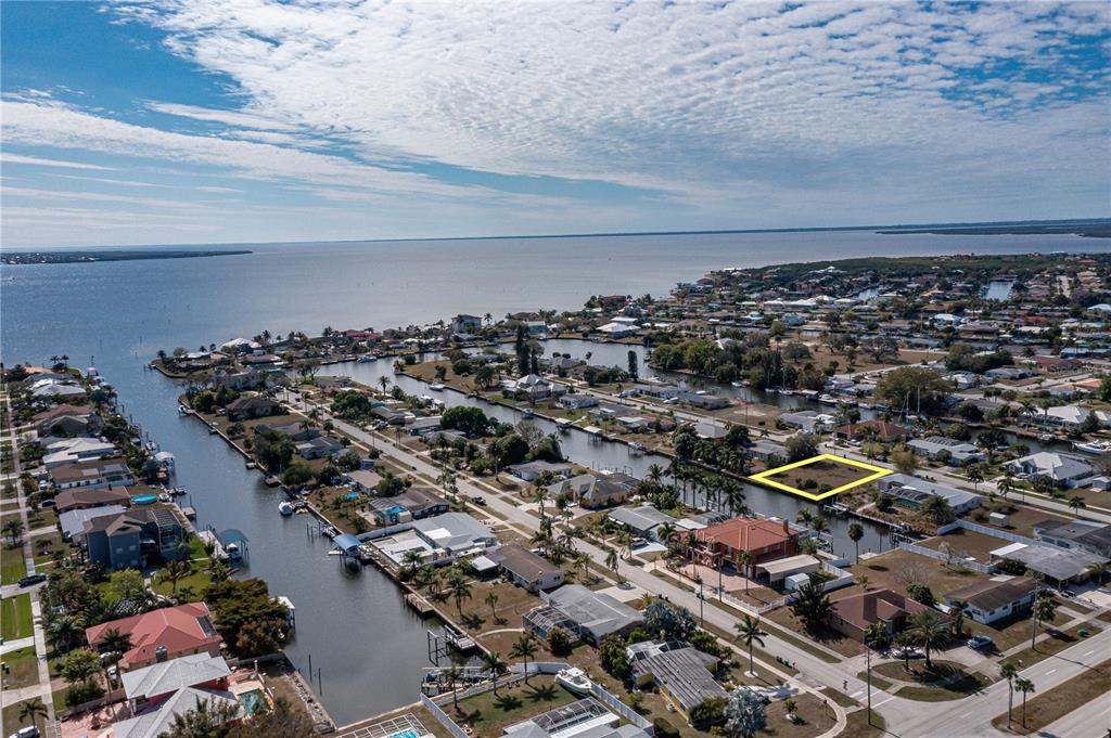 An aerial view shows a vacant waterfront lot highlighted in yellow within a residential neighborhood — 109 BALDWIN COURT SE, PORT CHARLOTTE, FL