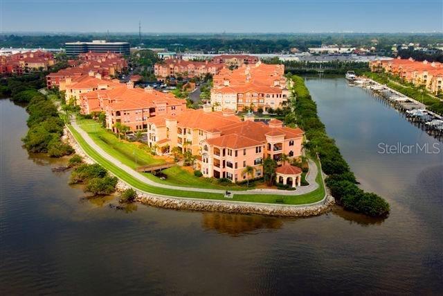 An aerial view shows a multi-story residential complex situated on a waterfront peninsula — 2723 VIA CAPRI UNIT 821, CLEARWATER, FL