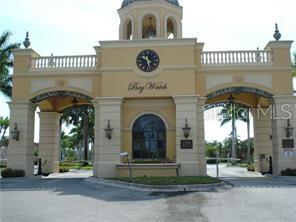 The exterior of a gated community entrance features a tan structure with a central clock — 2723 VIA CAPRI UNIT 821, CLEARWATER, FL