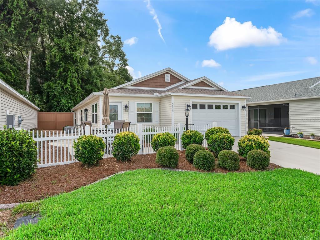 A single-story house with light yellow siding, a white garage, and a white picket fence — 5719 SPARTINA TERRACE, THE VILLAGES, FL