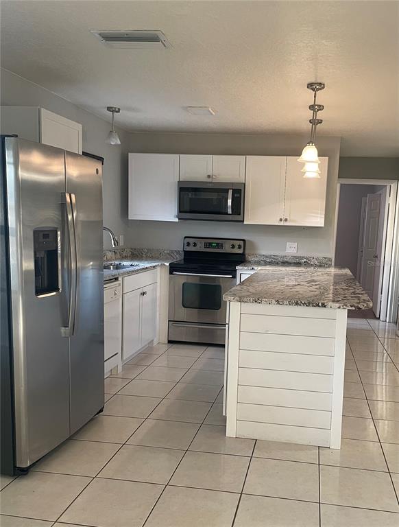 A kitchen features white cabinets, stainless steel appliances, granite countertops, and a shiplap-sided island — 1008 YORK COURT, BRANDON, FL