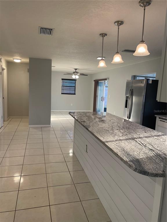 A kitchen island with a granite countertop sits in front of a tiled open-concept living area — 1008 YORK COURT, BRANDON, FL
