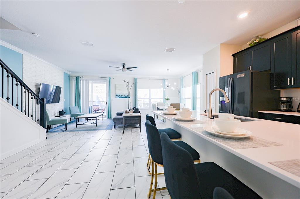 An open-concept living area features a kitchen island with bar stools and tile flooring — 1132 CHALLENGE DRIVE, DAVENPORT, FL