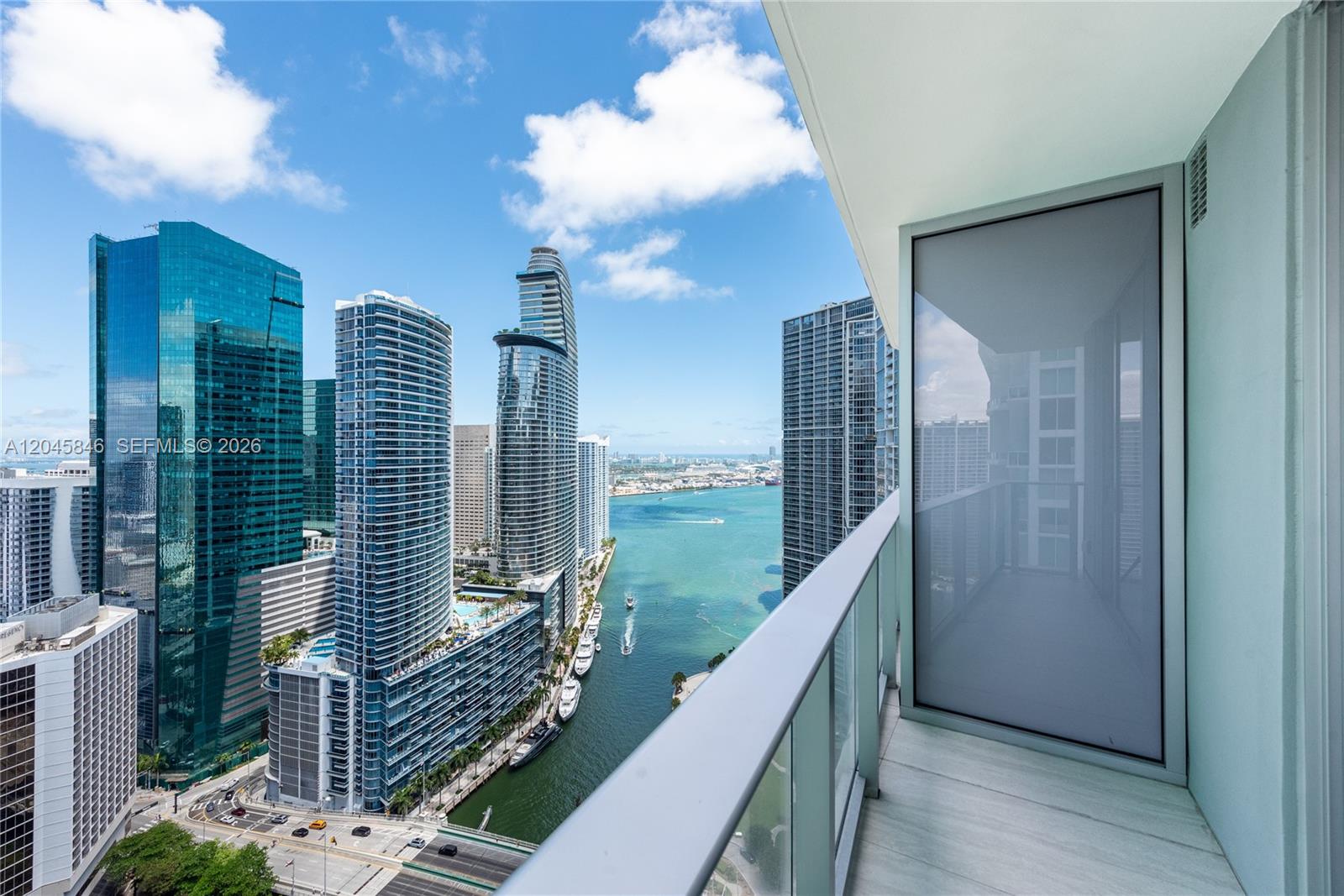 A high-rise balcony overlooks a city skyline, a waterway, and several glass skyscrapers — 77 SE 5th Street # 3604, Miami FL 33131, MIAMI, FL