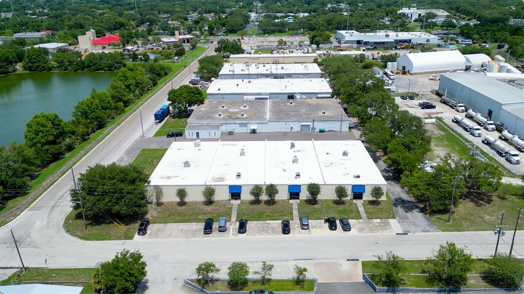 An aerial view shows a commercial warehouse complex with a parking lot and adjacent pond — 1603 SUNSHINE DRIVE, CLEARWATER, FL