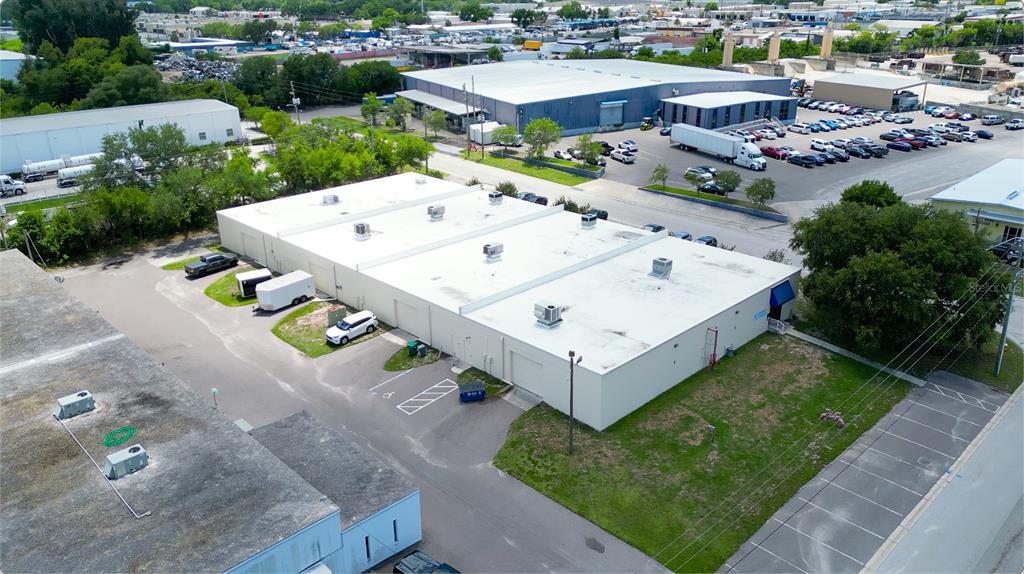 An aerial view shows a long, white commercial warehouse building with multiple rooftop HVAC units — 1603 SUNSHINE DRIVE, CLEARWATER, FL