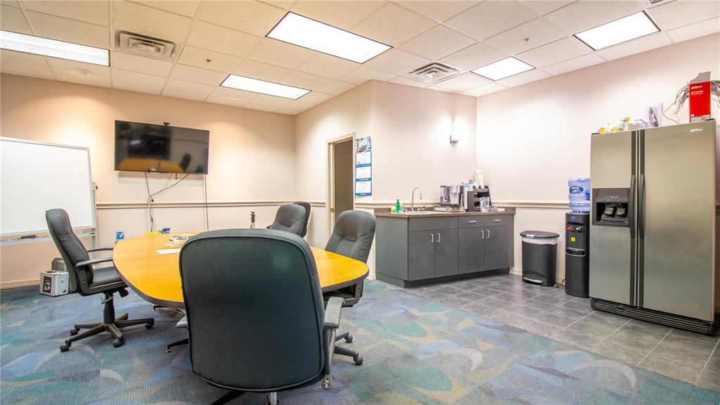 A conference room features a wooden table, office chairs, a kitchenette, and a refrigerator — 1603 SUNSHINE DRIVE, CLEARWATER, FL