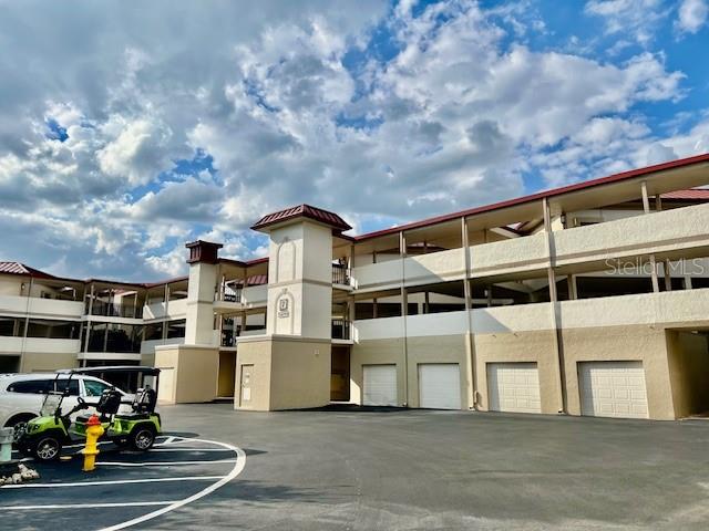 A multi-story apartment building with a parking garage and a golf cart in the foreground — 3270 SOUTHSHORE DRIVE UNIT 72B, PUNTA GORDA, FL
