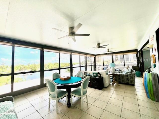 A sunroom with tile floors, a game table, and floor-to-ceiling windows overlooking a waterway — 3270 SOUTHSHORE DRIVE UNIT 72B, PUNTA GORDA, FL