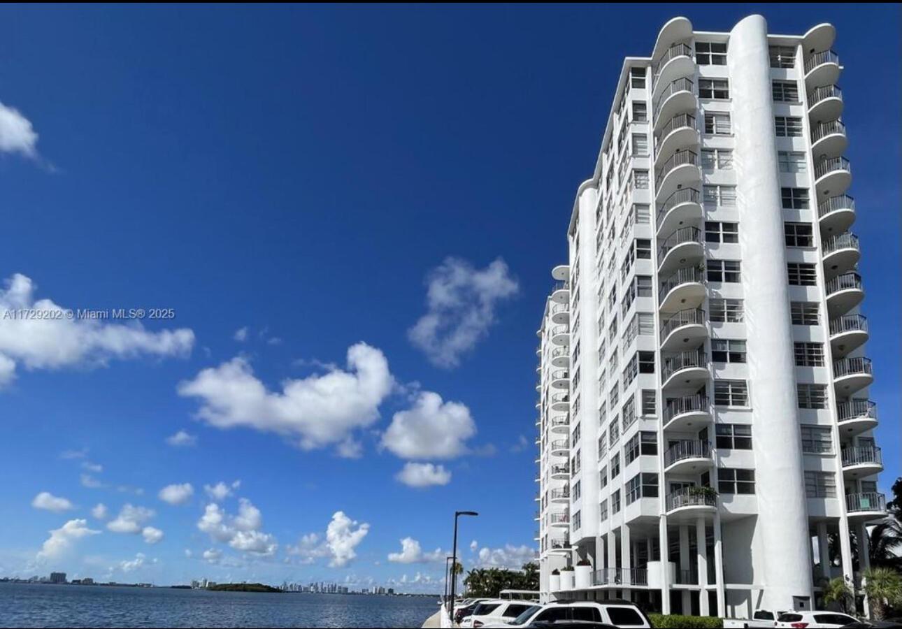 A tall white residential building stands next to a body of water under a sky — 11930 N Bayshore Drive, North Miami FL 33181, NORTH MIAMI, FL