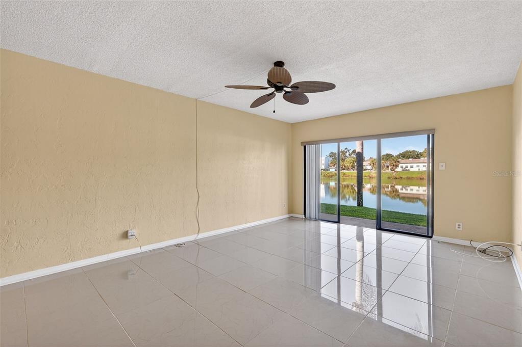 An empty room with beige walls, tile flooring, a ceiling fan, and sliding glass doors — 1749 S HIGHLAND AVENUE UNIT A5, CLEARWATER, FL
