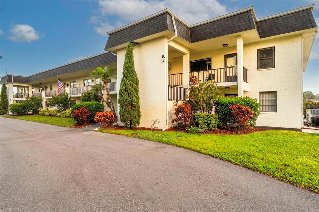 A two-story apartment building with a stucco exterior, balconies, and landscaped front lawn — 1749 S HIGHLAND AVENUE UNIT A5, CLEARWATER, FL
