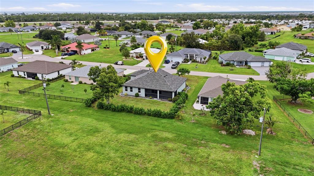 An aerial view shows a single-story suburban house with a gray roof and large backyard — 16146 GALIANO COURT, PUNTA GORDA, FL