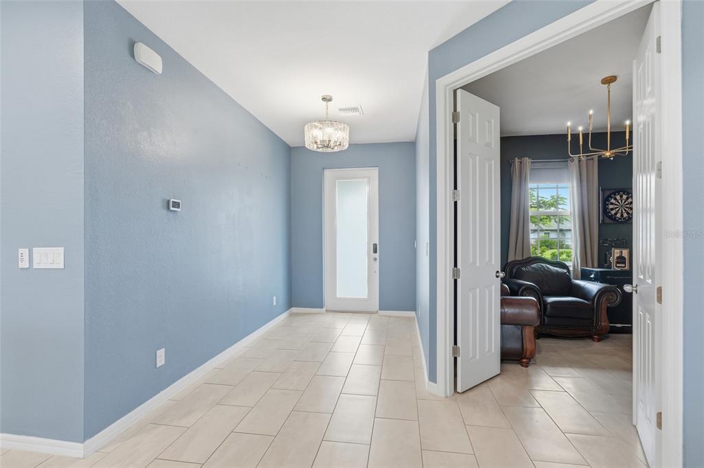 A blue-walled entryway with tile flooring leads to a front door and an adjacent room — 16146 GALIANO COURT, PUNTA GORDA, FL