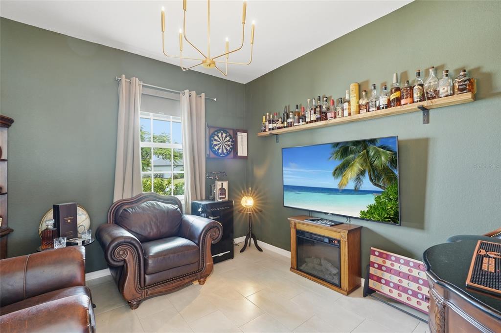 A lounge room features olive green walls, a leather armchair, a wall-mounted television, and liquor bottles — 16146 GALIANO COURT, PUNTA GORDA, FL